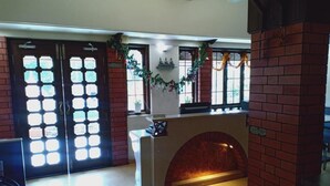 Un hall d’entrée avec une cheminée, une double porte dotée de panneaux de verre et une colonne en briques.