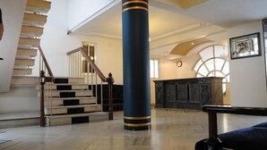 Un intérieur spacieux agrémenté d’un grand escalier, d’une imposante colonne bleue et d’une cheminée.