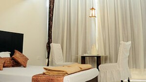 Une chambre d’hôtel avec un lit, une table de chevet, une chaise et un ventilateur de plafond.