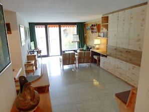 Un amplio salón con sofá, sillas, un mueble de madera y una mesa de comedor.