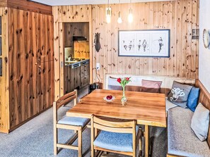 Ein Holzinterieur mit Esstisch, Stühlen, einer Bank und einer Küchenzeile.