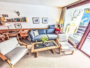 Una sala de estar acogedora con un sofá, sillones, una mesa de centro y una estantería.