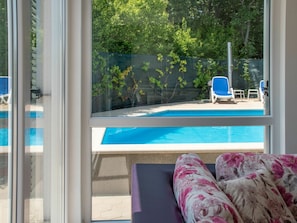 Enjoy a restful stay with a view of the pool from this room, featuring a comfortable bed and a large window.