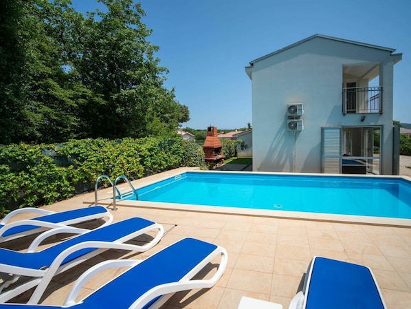 Relax by the serene pool surrounded by lush greenery and comfortable lounge chairs.