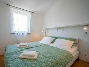 Cozy retreat with a single bed, green floral-patterned bedspread, and white towels.
