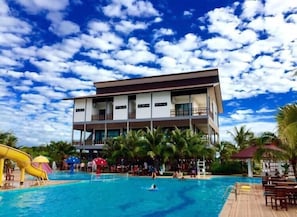 Un hôtel moderne doté d’un espace piscine, comprenant un toboggan et des chaises longues.