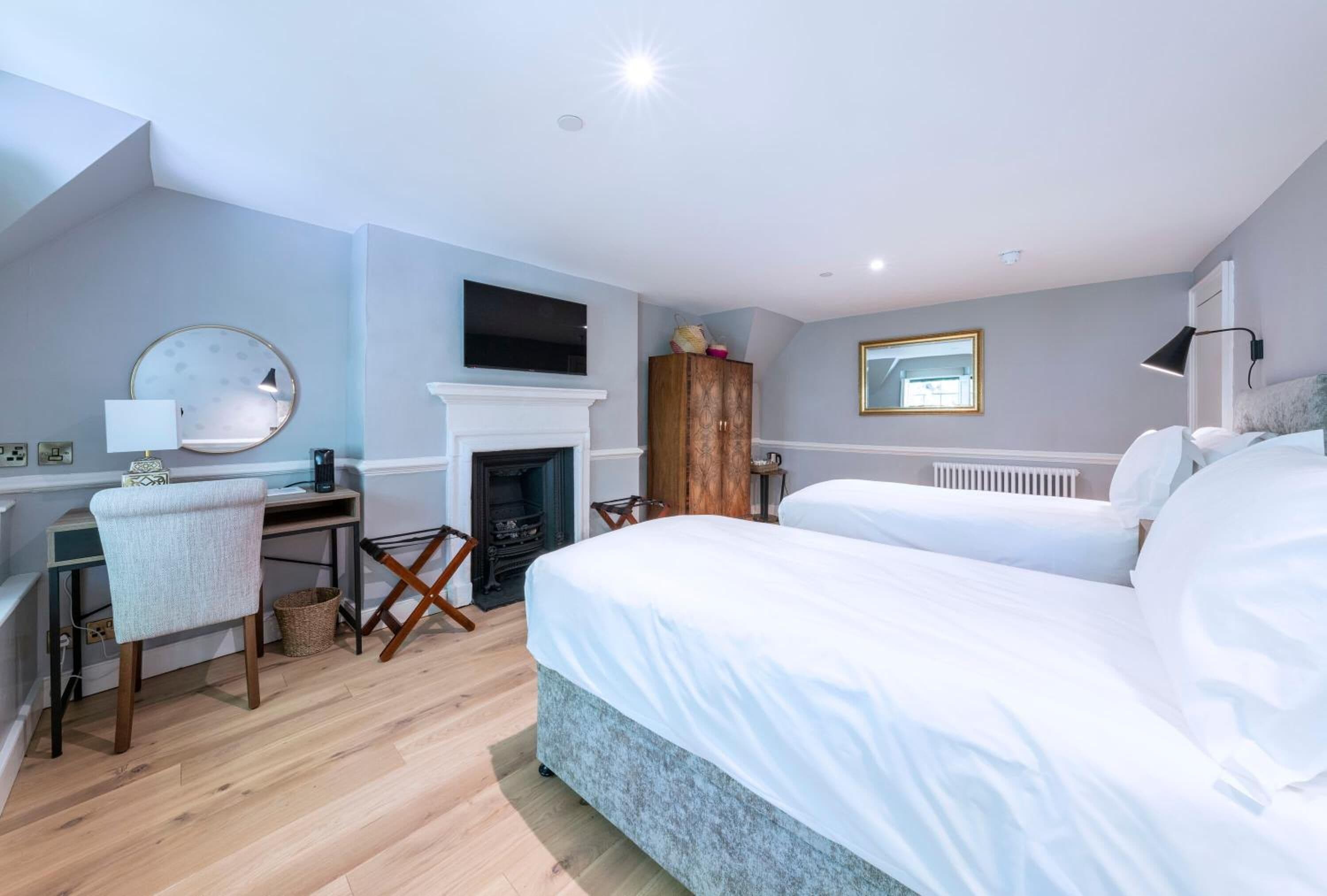 A bedroom with a bed, a desk, a chair, a fireplace, and a television.
