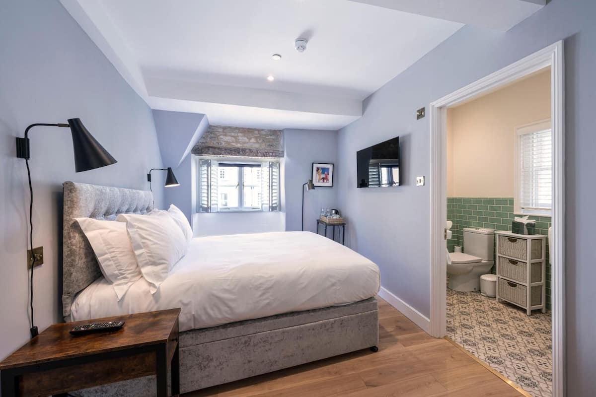 A bedroom with a bed, bedside table, and a window.
