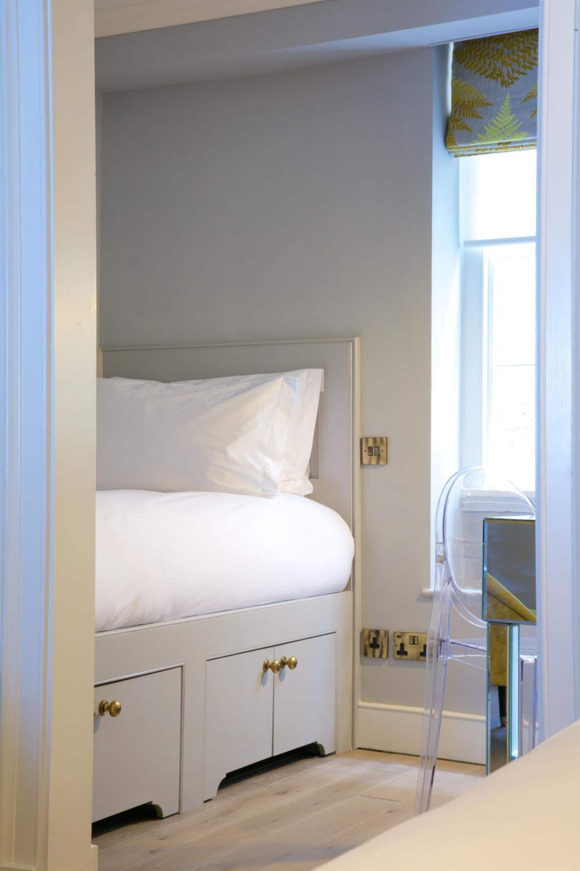 A bedroom with a bed, a wardrobe, and a window with a curtain.