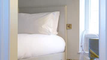 A bedroom with a bed, a wardrobe, and a window with a curtain.