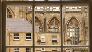 A window with a view of a building featuring Gothic architecture, including pointed arches and detailed stonework. - Eight (Bath)