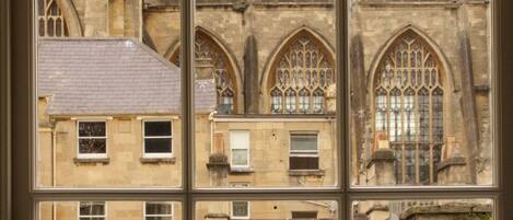 Una ventana con vistas a un edificio de arquitectura gótica, con arcos apuntados y ornamentación de piedra detallada.