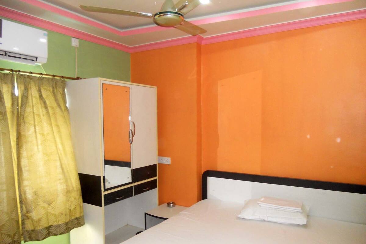 Una habitación con cama, armario, ventilador de techo y ventana con cortinas.