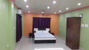 A bedroom with a bed, a wardrobe, a ceiling fan, and an air conditioning unit. - Hotel Gitanjali Raiganj (Raiganj)