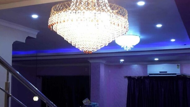A grand chandelier in a spacious lobby with a curved ceiling and a reception desk. - Hotel Gitanjali Raiganj (Raiganj)