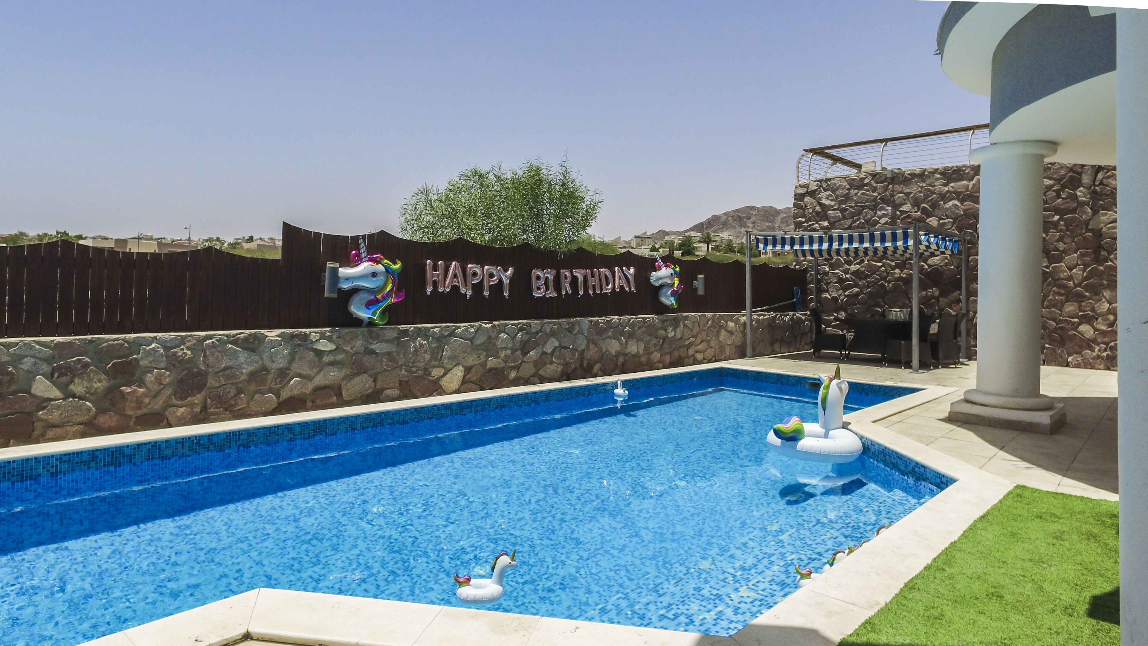 Una piscina amb un cartell de 'Happy Birthday', una decoració de unicorn i un flotsam de cigne.
