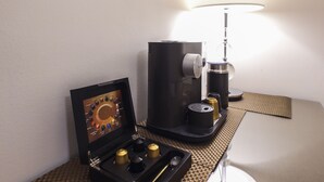 A coffee machine and a coffee pod holder on a table with a lamp.