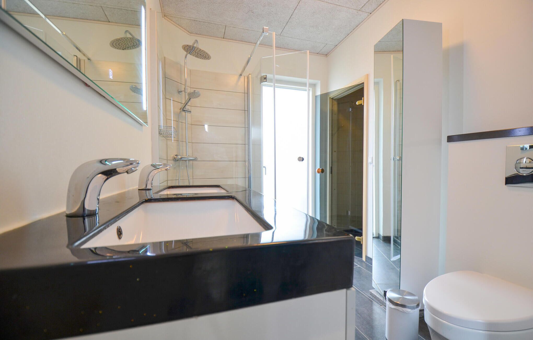 A modern bathroom with a black countertop sink, a white toilet, and a glass shower enclosure.