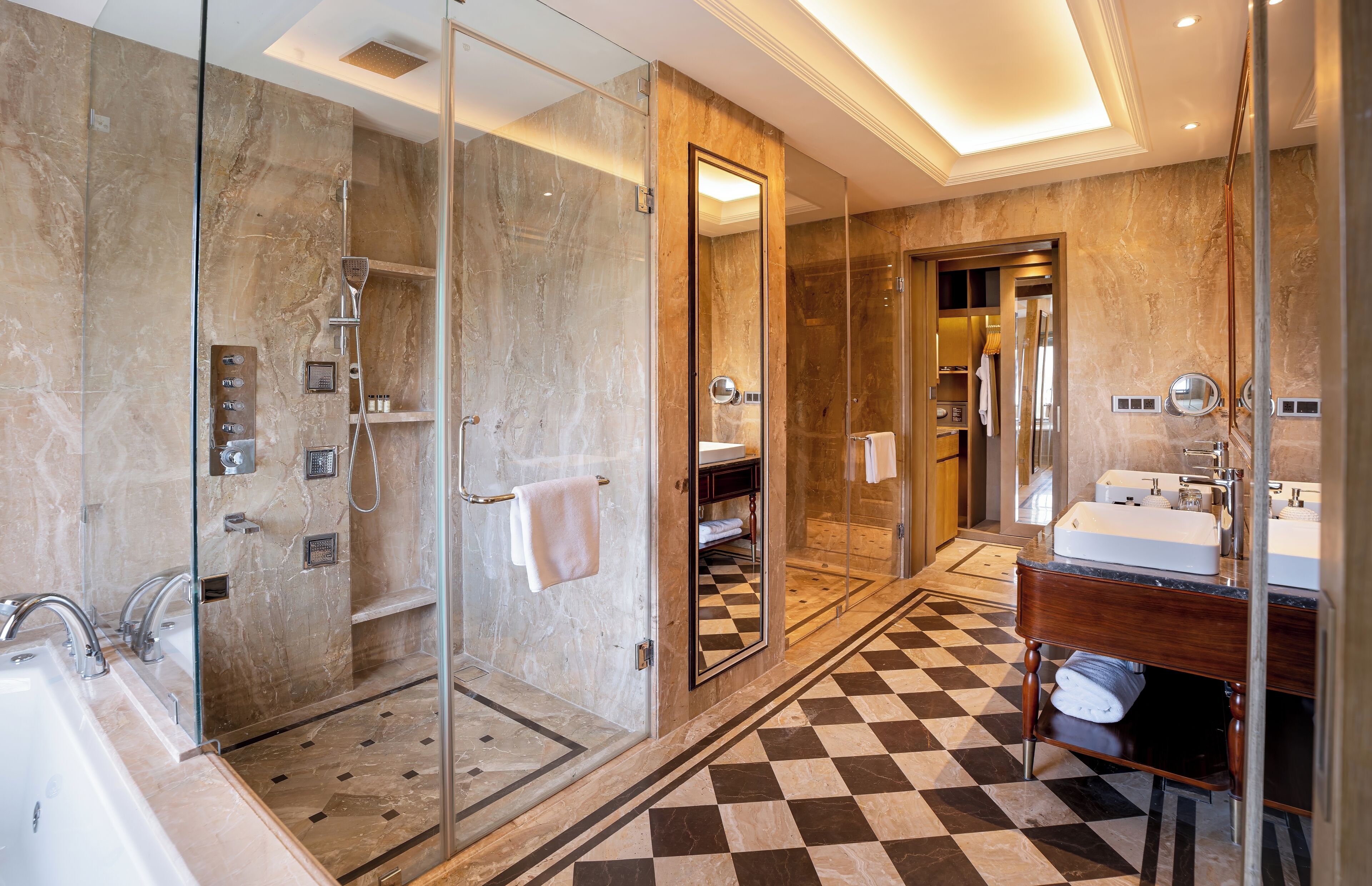 A modern bathroom with a glass-enclosed shower, a checkered floor, a vanity with a mirror, and a sink.