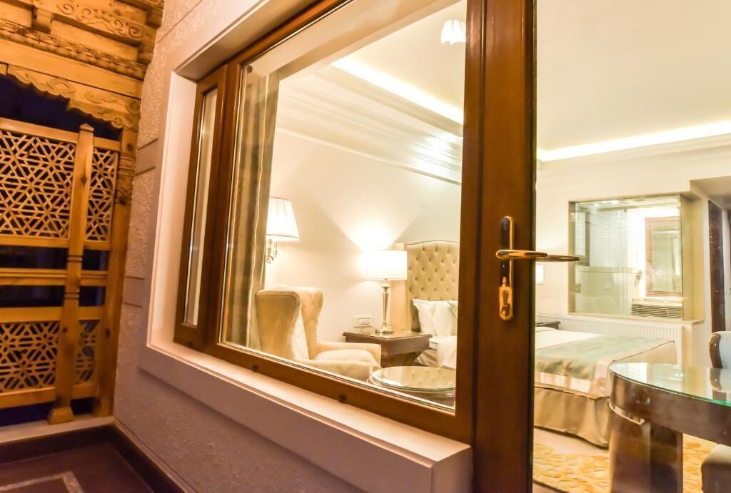 Una camera d'albergo con un'ampia finestra, un letto, una sedia e un comodino.