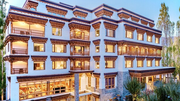 A multi-story building with a traditional architectural style, featuring balconies and large windows. - The Indus Valley (Leh)