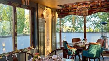 Comedor con una mesa larga, sillas y vista a áreas verdes.