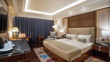 Habitación de hotel con una cama grande, un escritorio con una silla, una mesita pequeña y una lámpara.