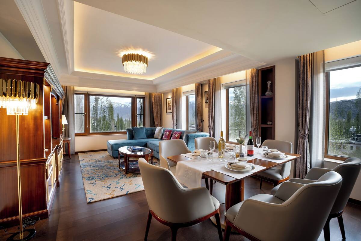 A modern living room with a dining area, large windows, and a view of mountains.