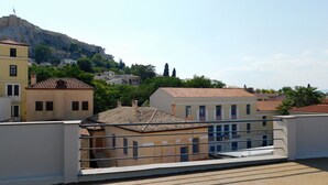 A residential area with buildings, a prominent hill, and a flag on top.