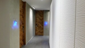 A hallway with a wooden door, a textured wall, and a light fixture on the ceiling.