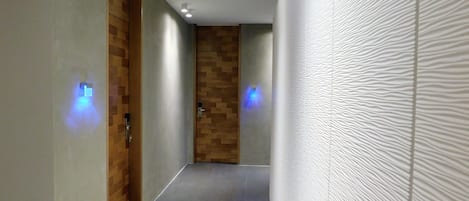 A hallway with a wooden door, a textured wall, and a light fixture on the ceiling.