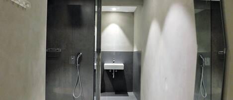 A modern bathroom with a glass shower enclosure, a white sink, and a handheld showerhead.