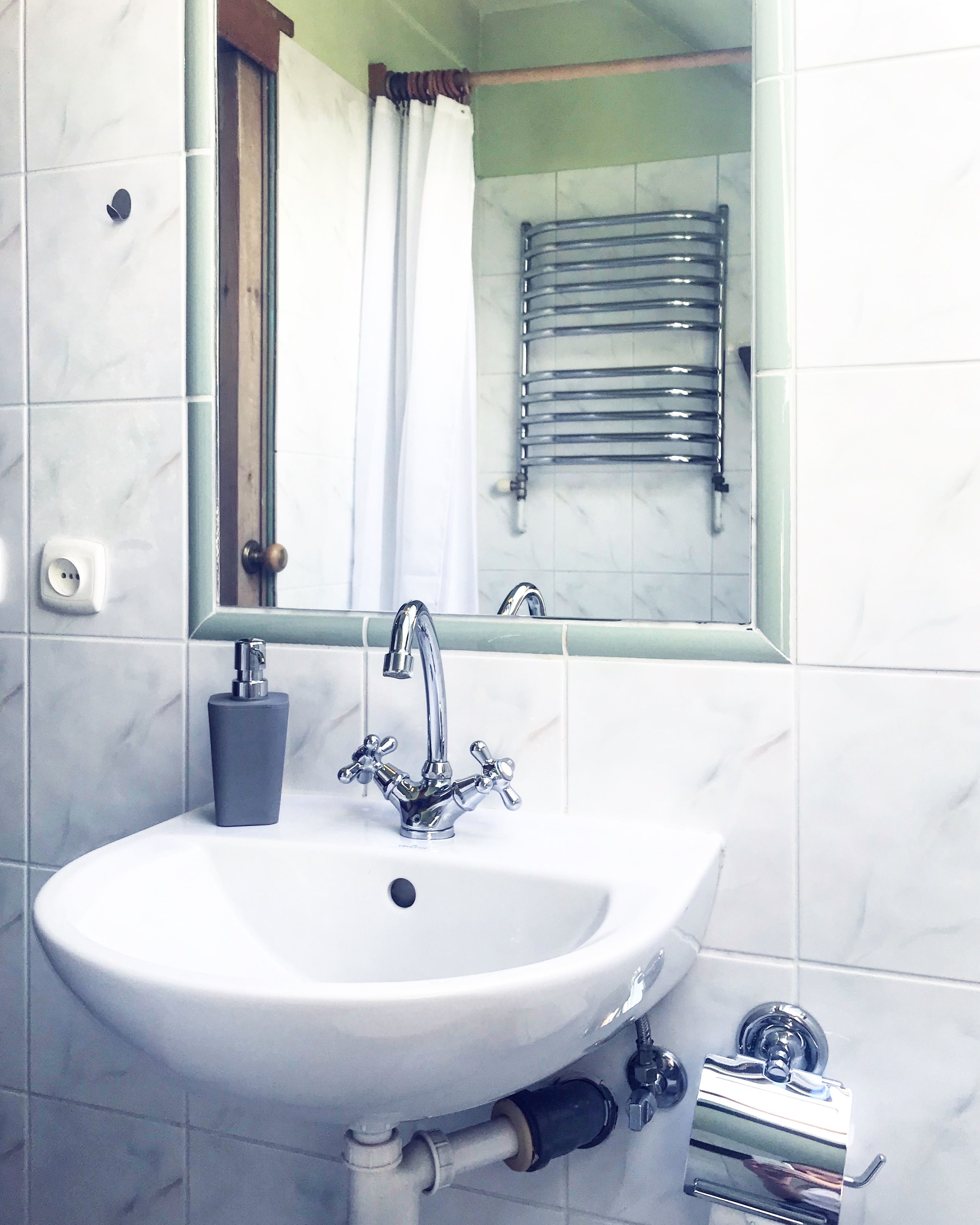 A bathroom with a white sink, chrome faucet, and a mirror above it.