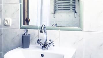 A bathroom with a white sink, chrome faucet, and a mirror above it.