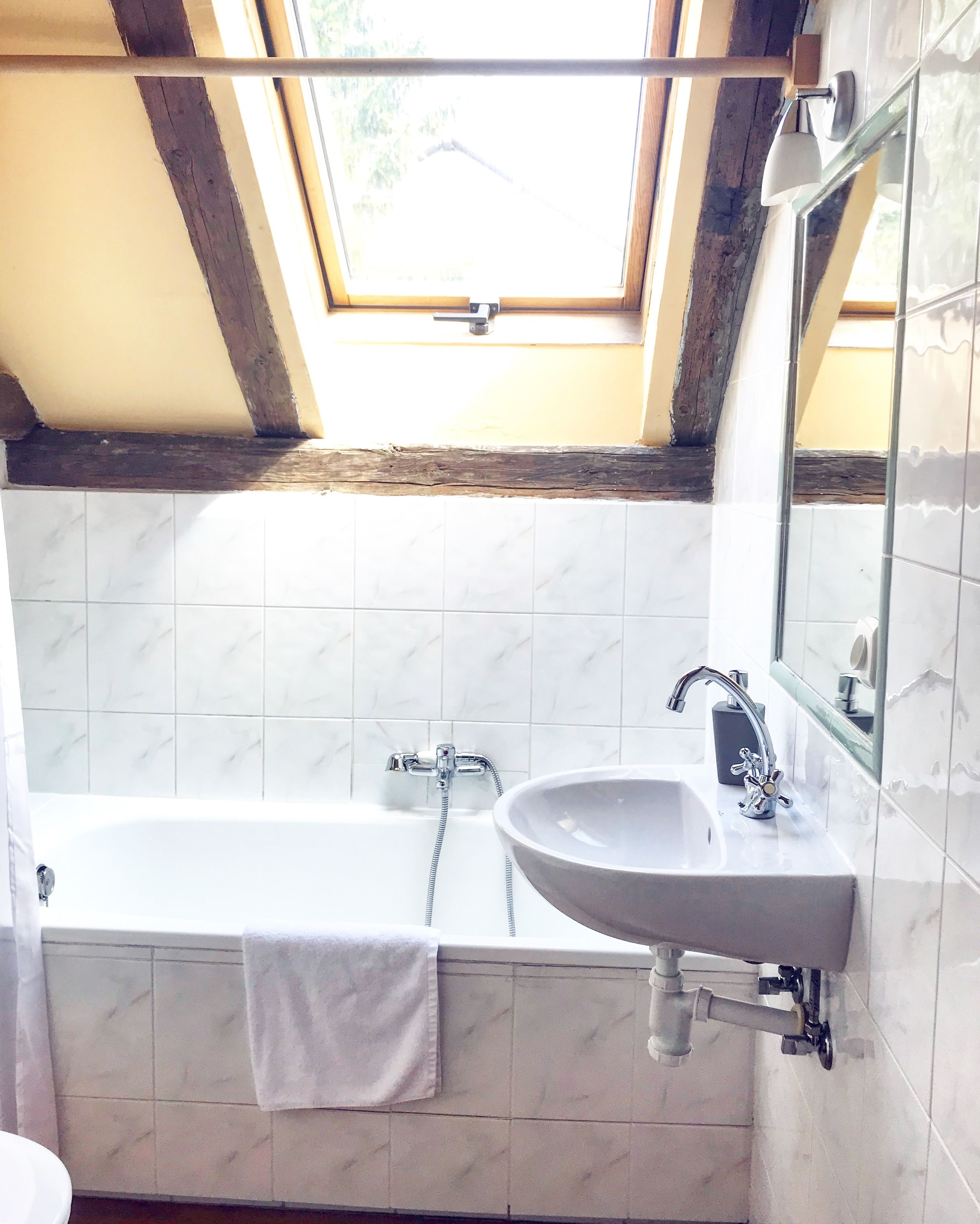 Un baño con una bañera, un lavabo y una ventana sobre la bañera.