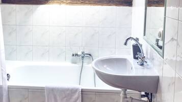 Un baño con una bañera, un lavabo y una ventana sobre la bañera.