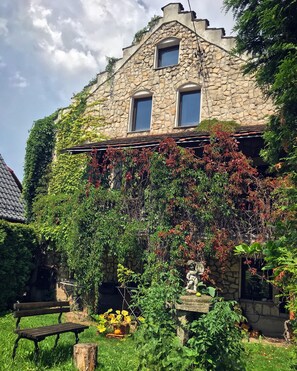 A stone building with ivy-covered walls and a small statue in the garden. - Dworek Adamski (Walbrzych)