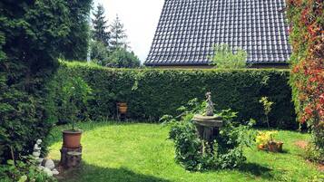 Un jardin avec une statue, une plante en pot et une haie.