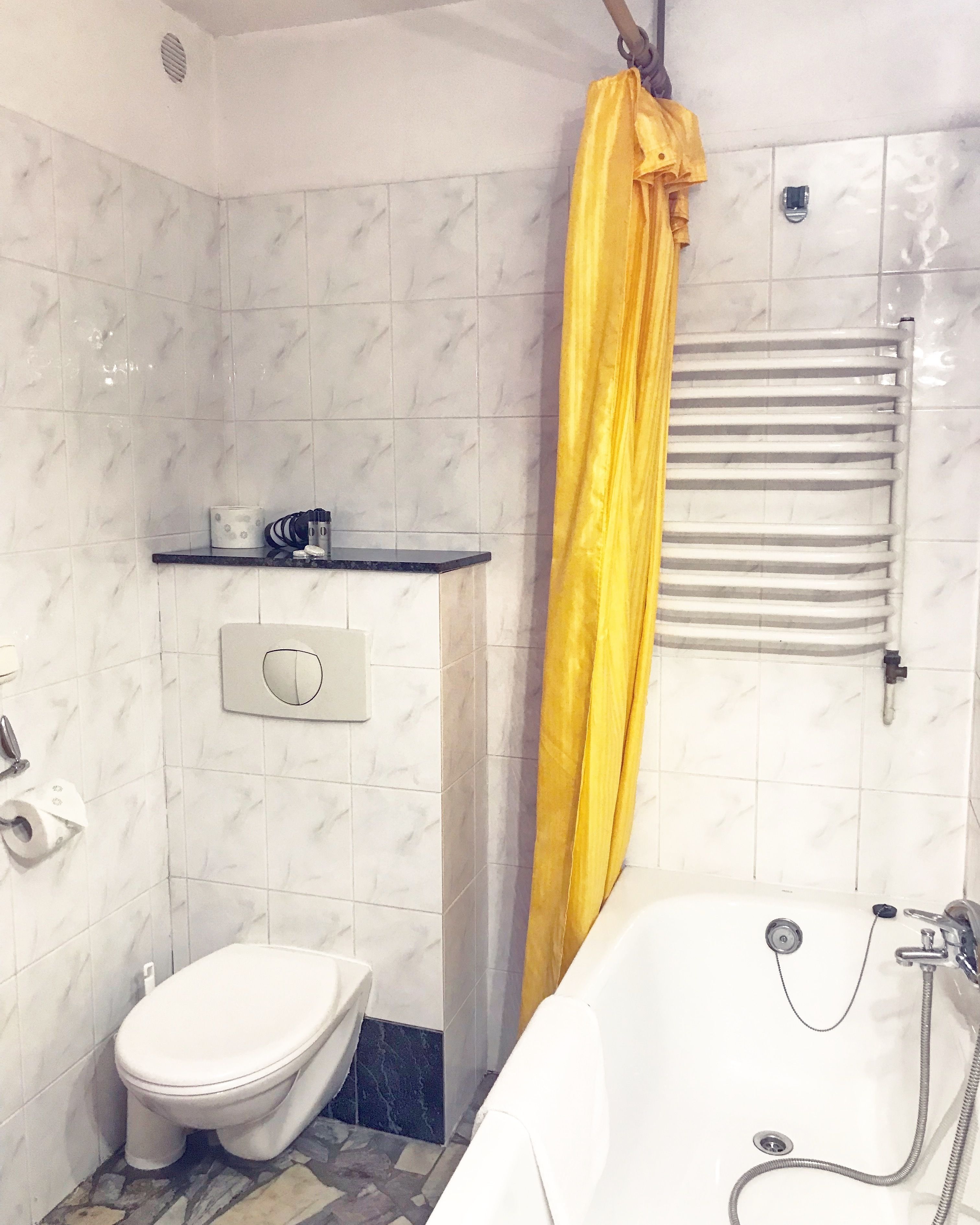 Un baño con inodoro, bañera, ducha, toallero y dispensador de jabón.