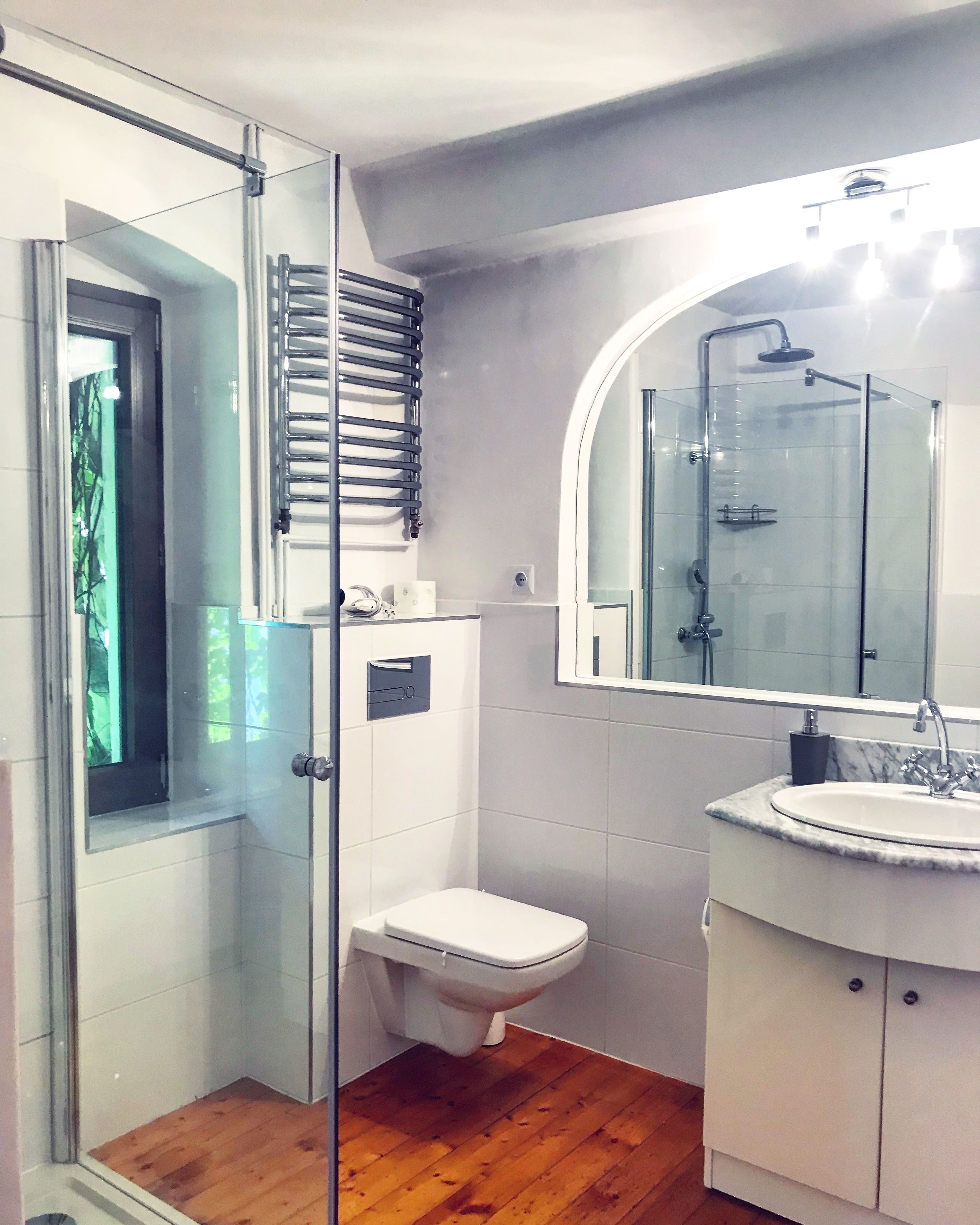 Un baño moderno con cabina de ducha de vidrio, inodoro y tocador con lavamanos.