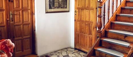 A hallway with wooden doors, a staircase, and a patterned rug.