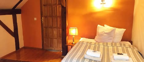 Un dormitorio con cama, mesita de noche, lámpara, puerta y alfombra estampada.