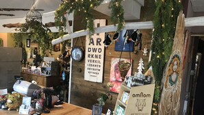 Interior acogedor de una tienda rústica con un mostrador de madera que exhibe varios artículos, un reloj y un letrero para los chocolates artesanales 'omnom'.