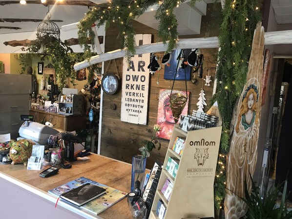 Interior acogedor de una tienda rústica con un mostrador de madera que exhibe varios artículos, un reloj y un letrero para los chocolates artesanales 'omnom'.