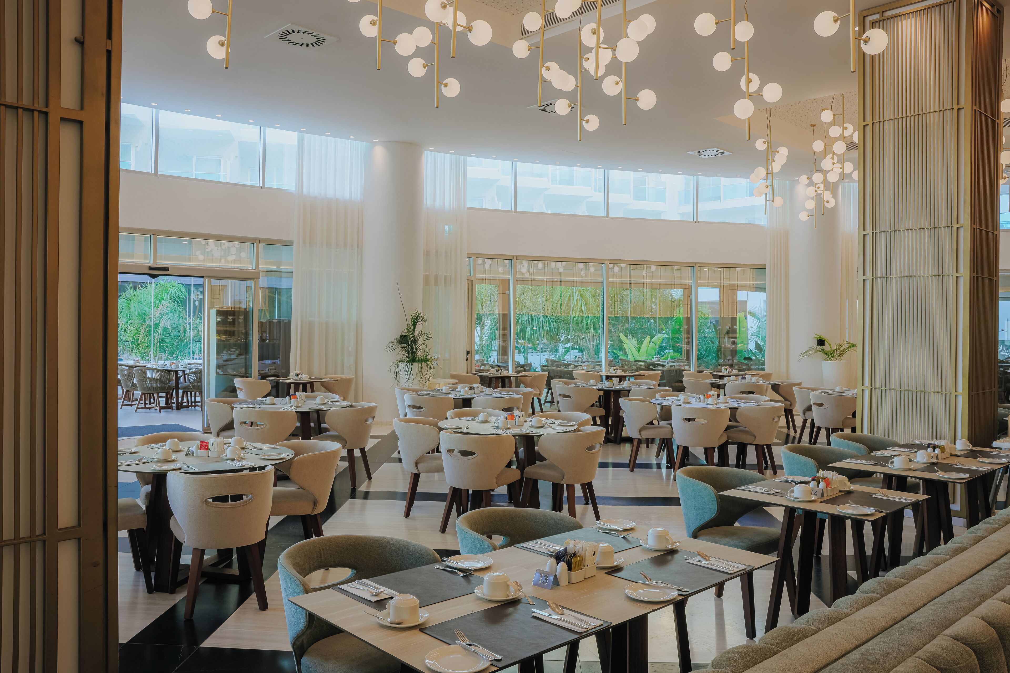A spacious restaurant with high ceilings, large windows, and modern lighting fixtures.