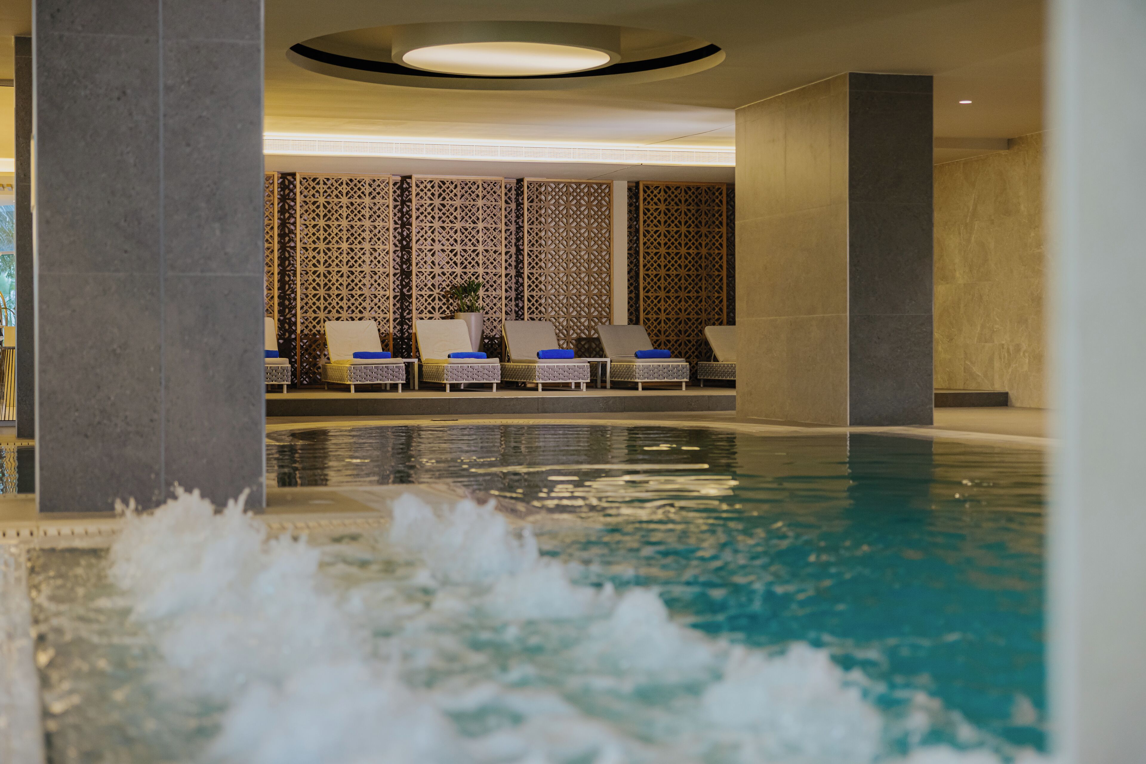 Zona piscina con lettini e una parete decorativa.