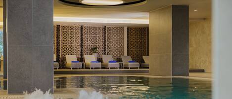 A pool area with lounge chairs and a decorative wall.