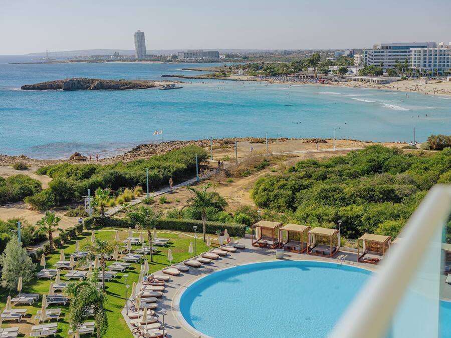 Un resort con piscina, tumbonas y vistas a la playa y el océano.