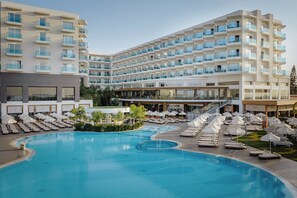 Un hotel con una piscina grande, varios balcones y tumbonas.