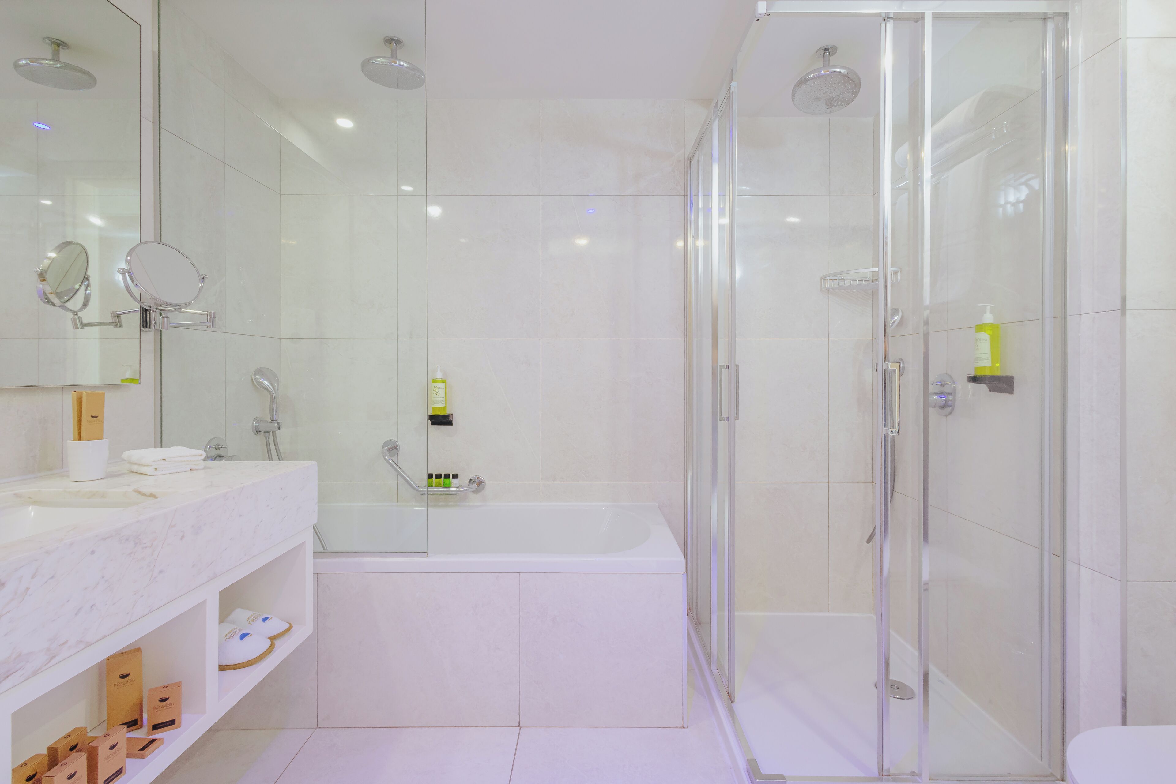 A modern bathroom with a glass-enclosed shower, a white bathtub, and a vanity with a mirror.